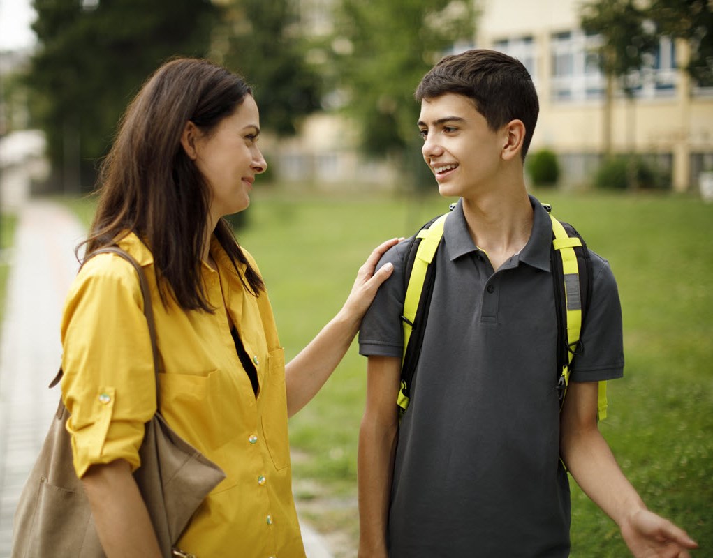 Mom and teenage son having talk about migraine as they walk to school