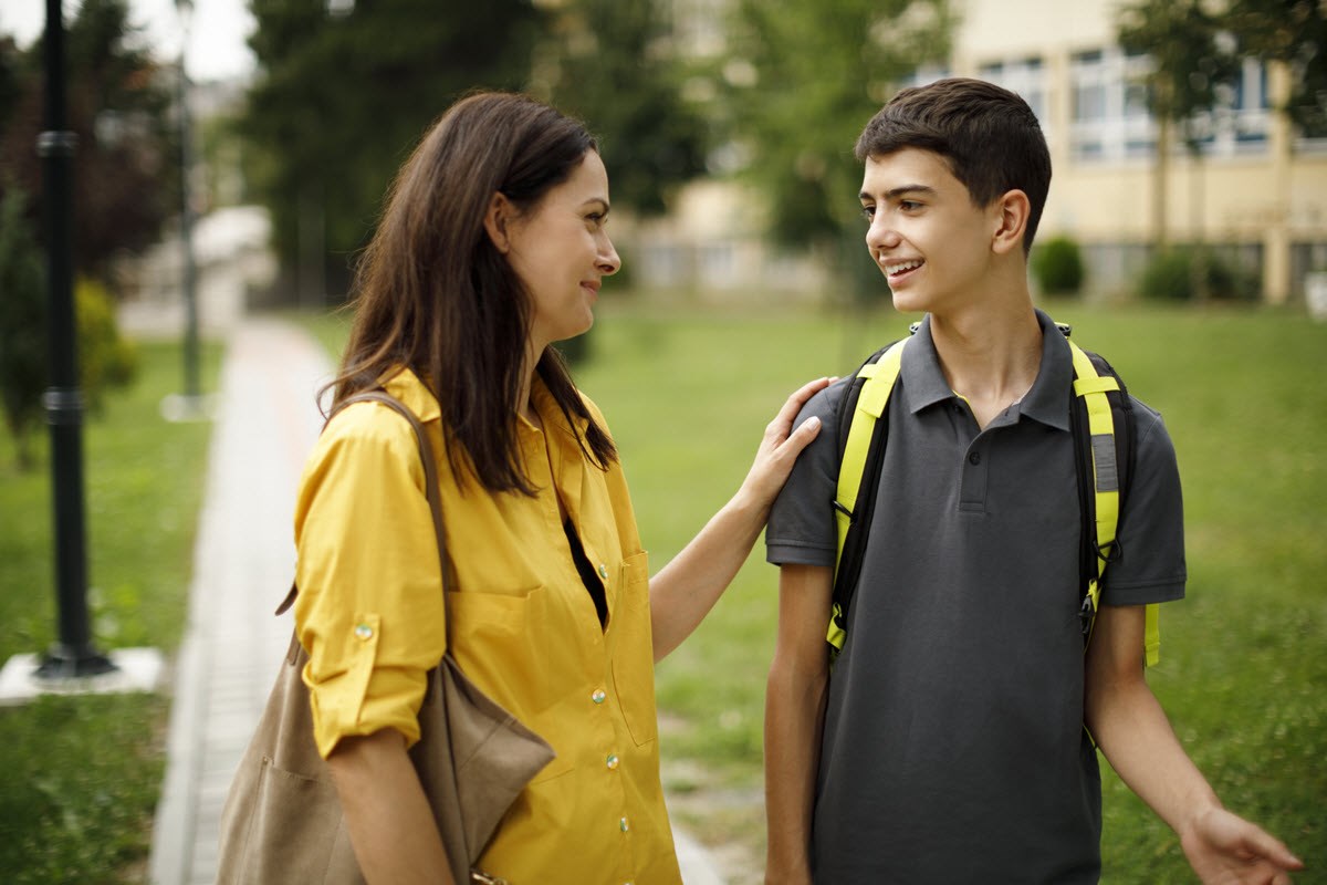 Mom and teenage son having talk about migraine as they walk to school