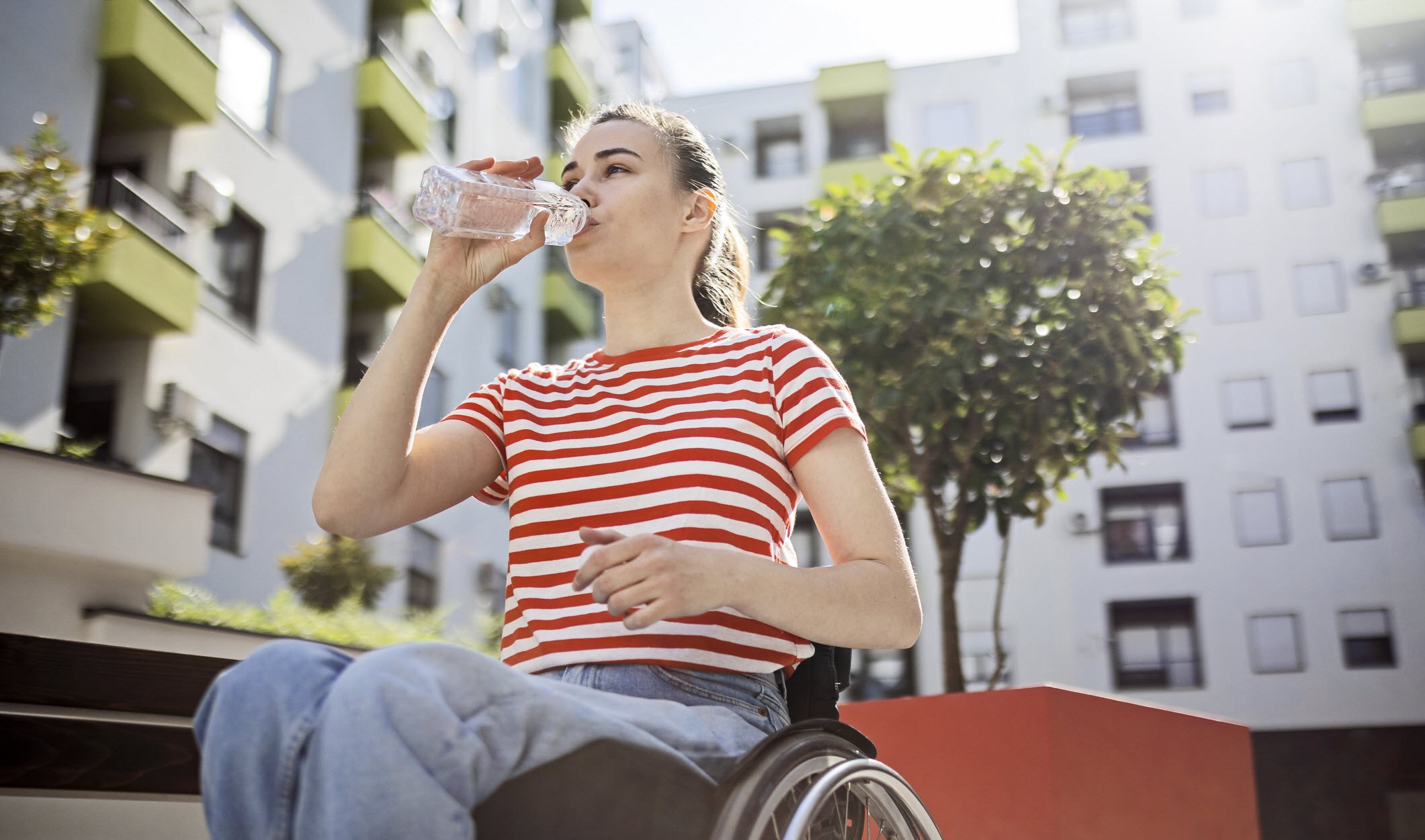 A woman in wheelchair drinking water to avoid triggering migraines