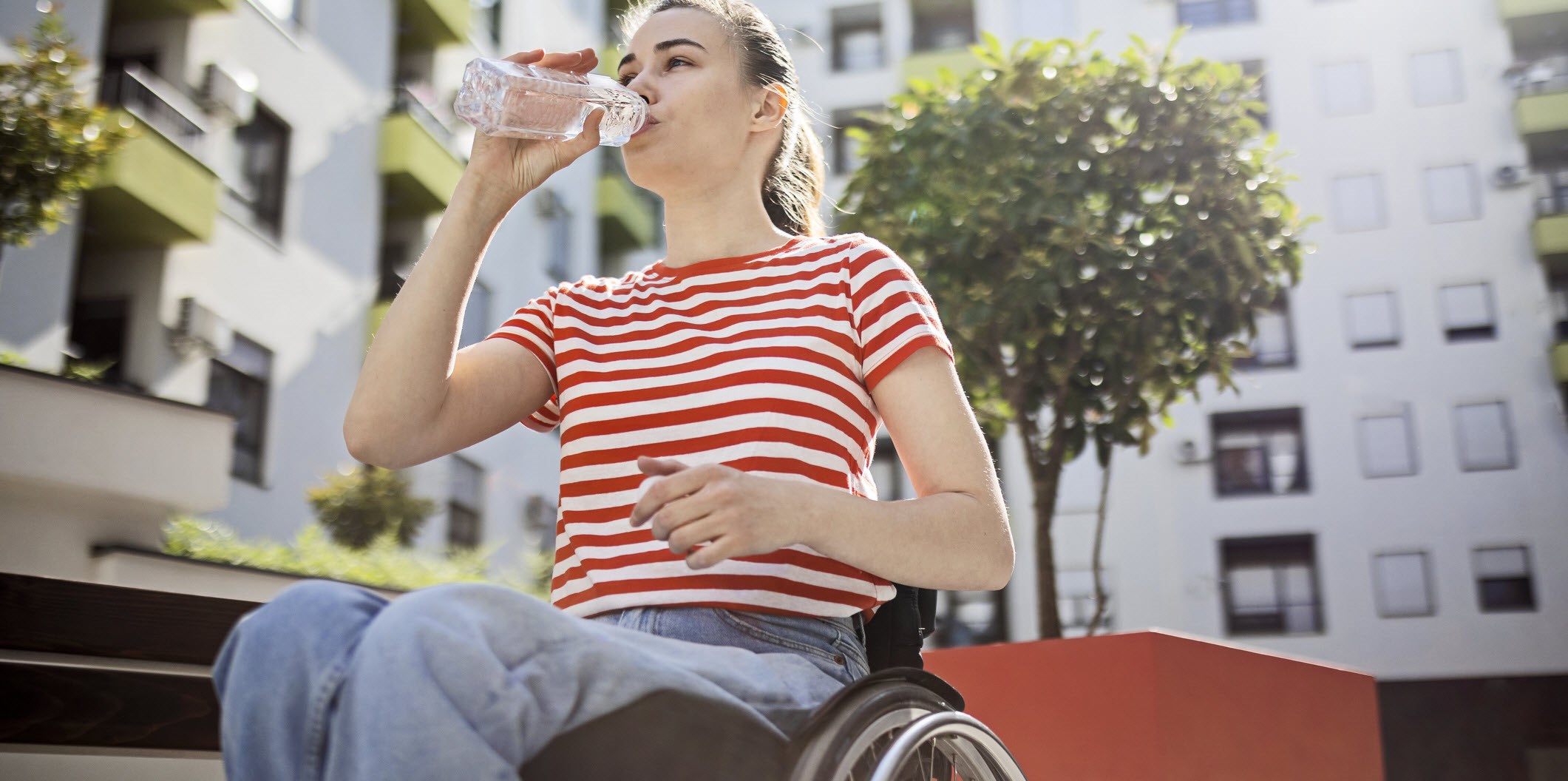 A woman in wheelchair drinking water to avoid triggering migraines