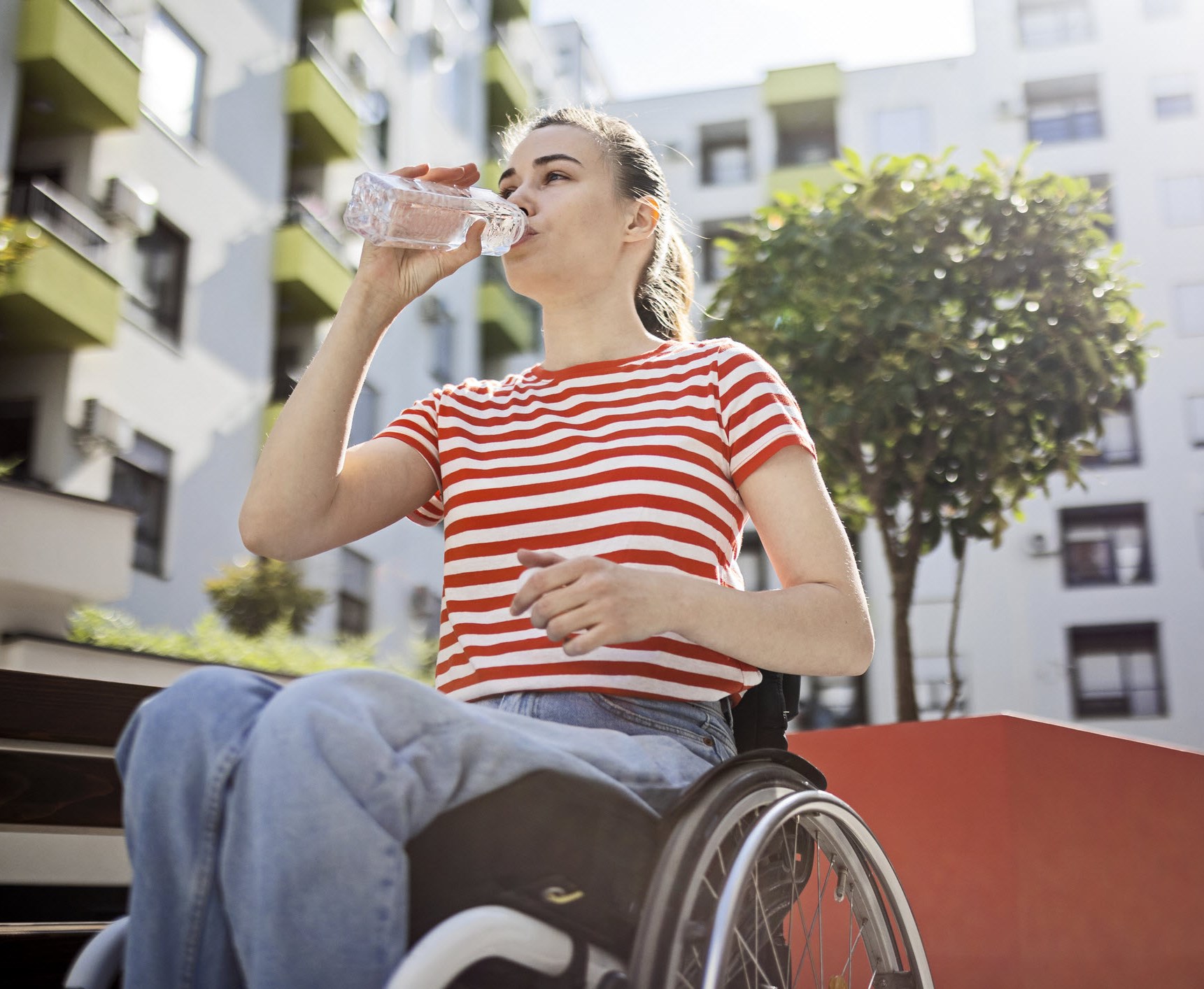 A woman in wheelchair drinking water to avoid triggering migraines