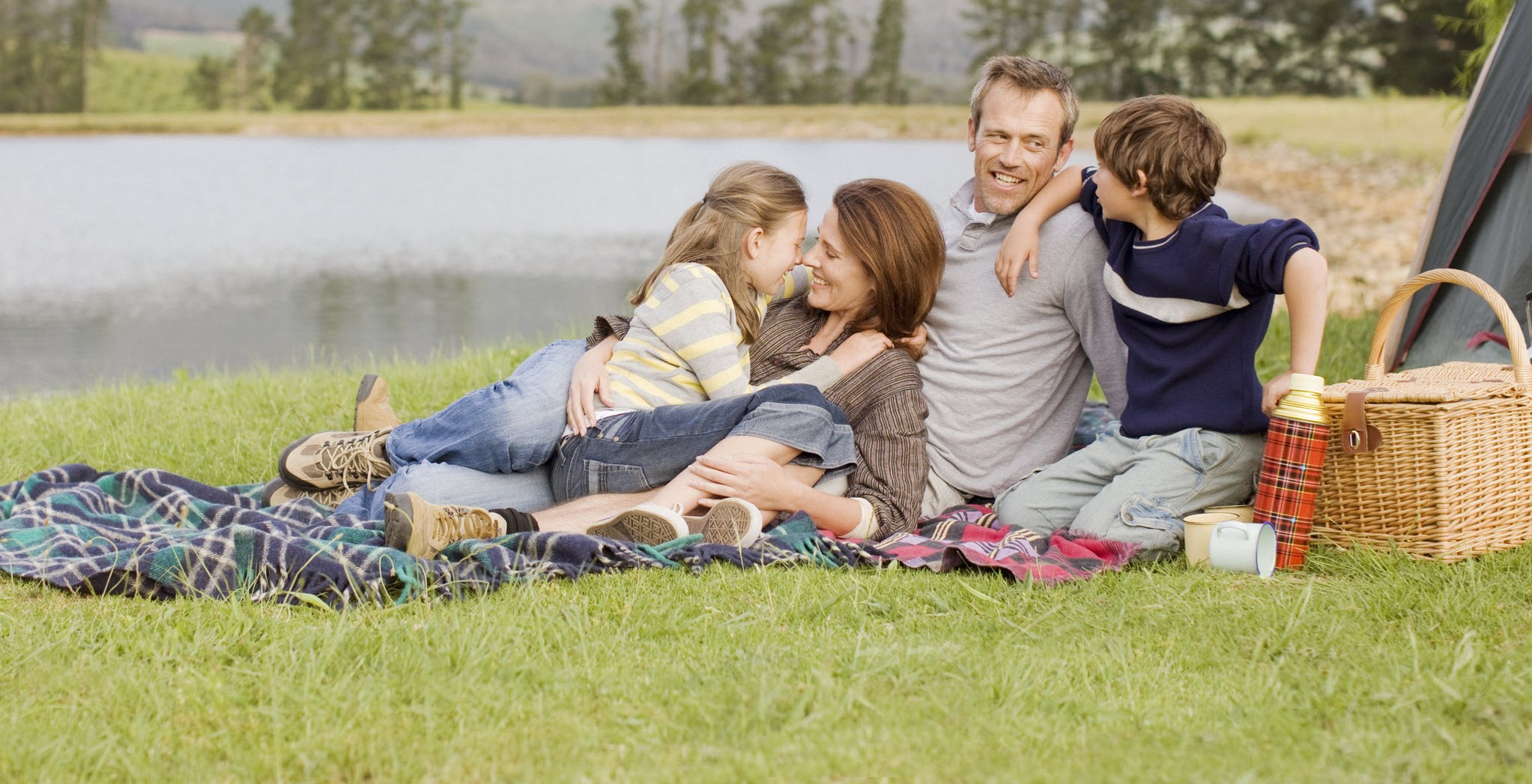 Happy family having picnic by the river, enjoying the weekend, despite migraine.