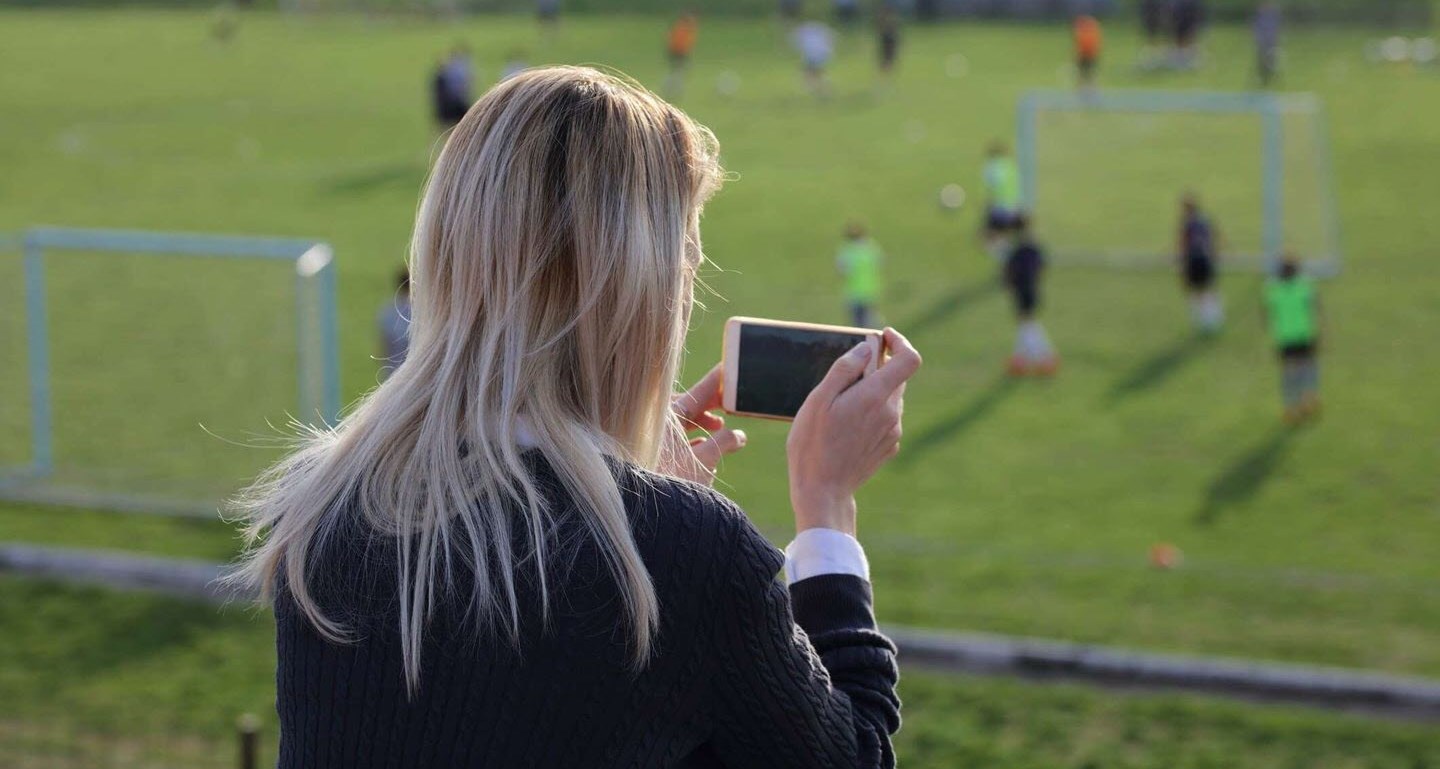 Mom with chronic migraine taking photos of her children playing soccer after school 