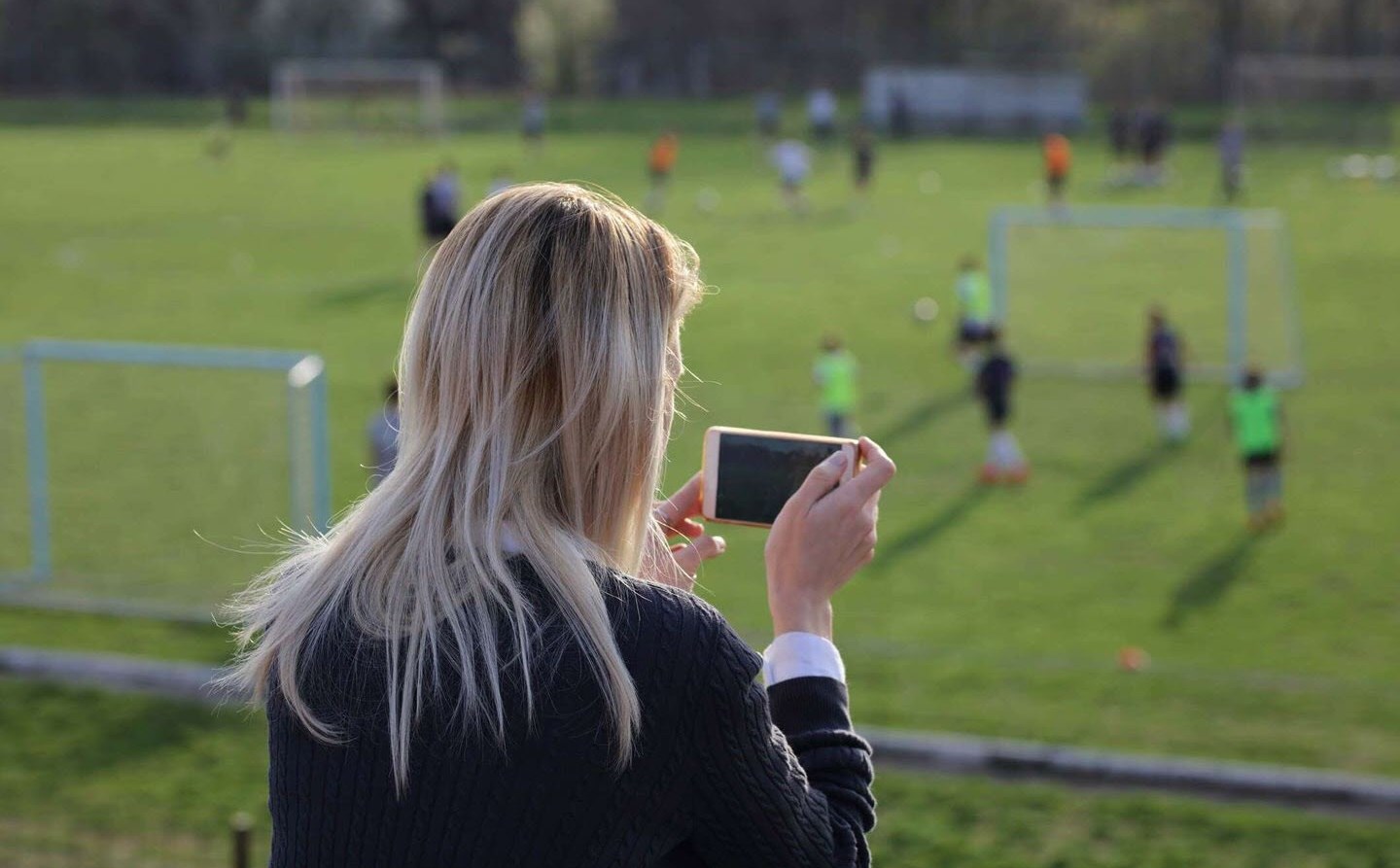 Mom with chronic migraine taking photos of her children playing soccer after school 