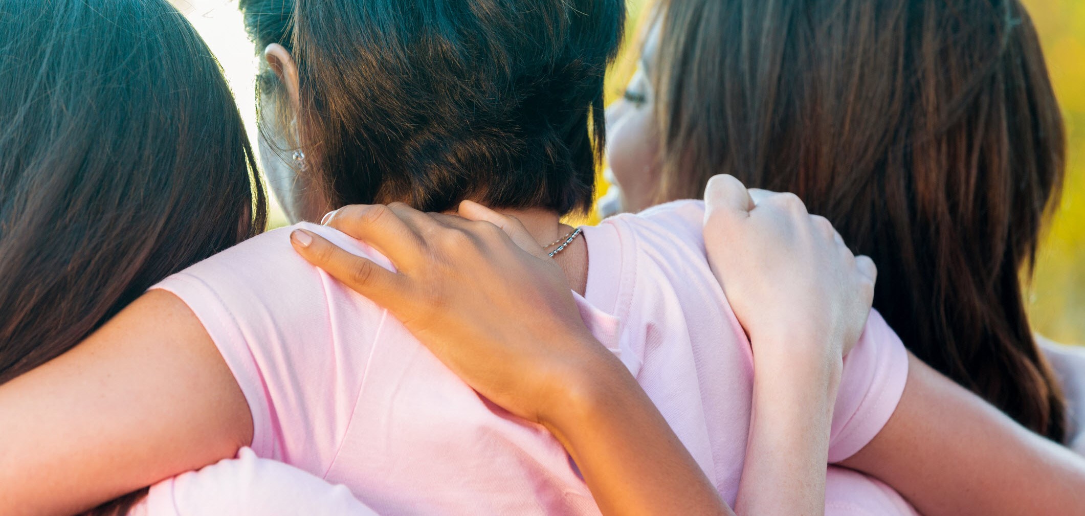 Three women with ADHD share a group hug at a social gathering.