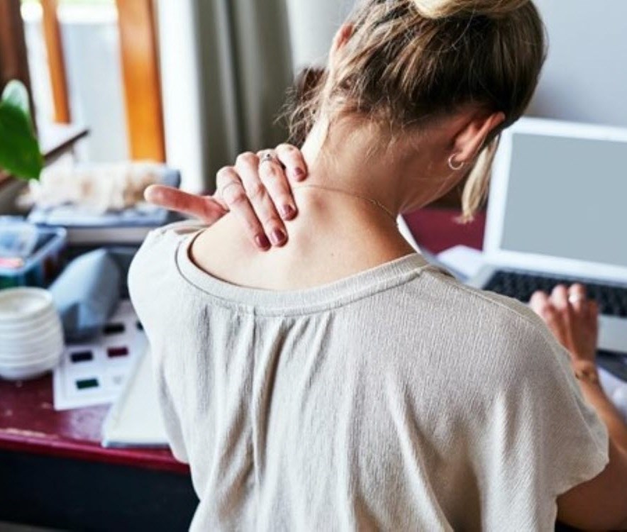 Woman at desk massages her neck to ease her pain and tension