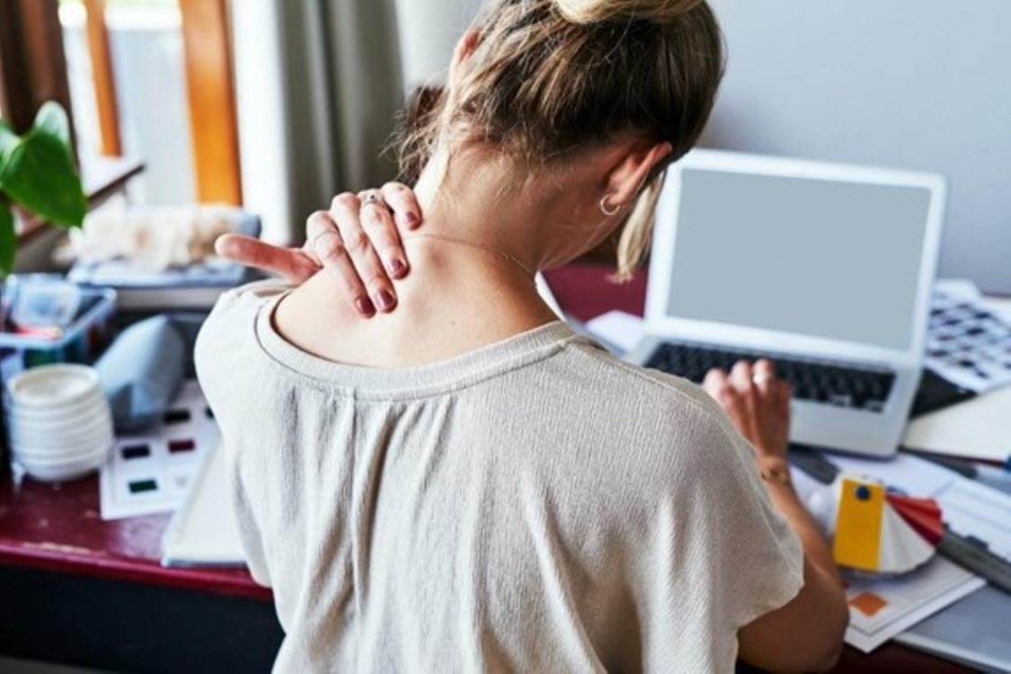 Woman at desk massages her neck to ease her pain and tension