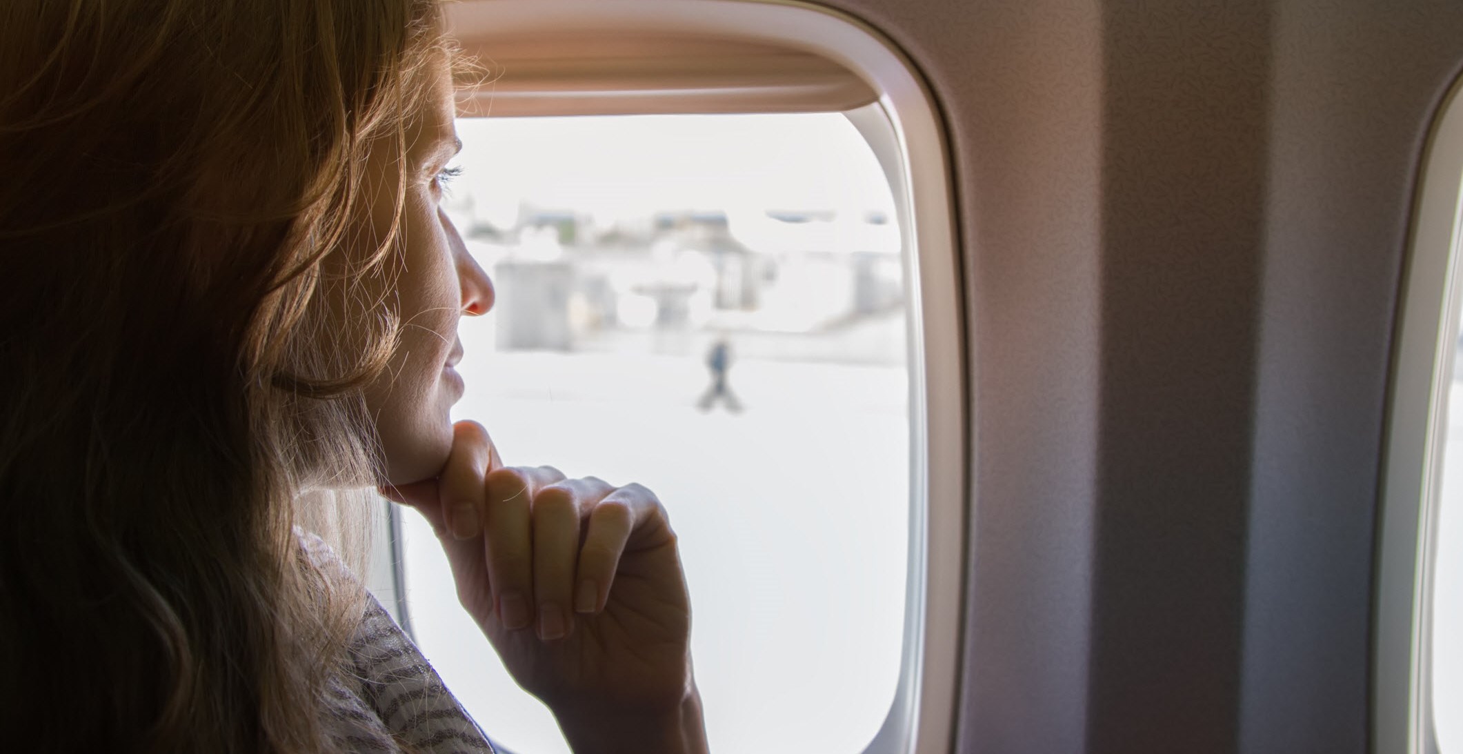 Woman looks out of plane window, confident of her migraine-friendly travelling plans