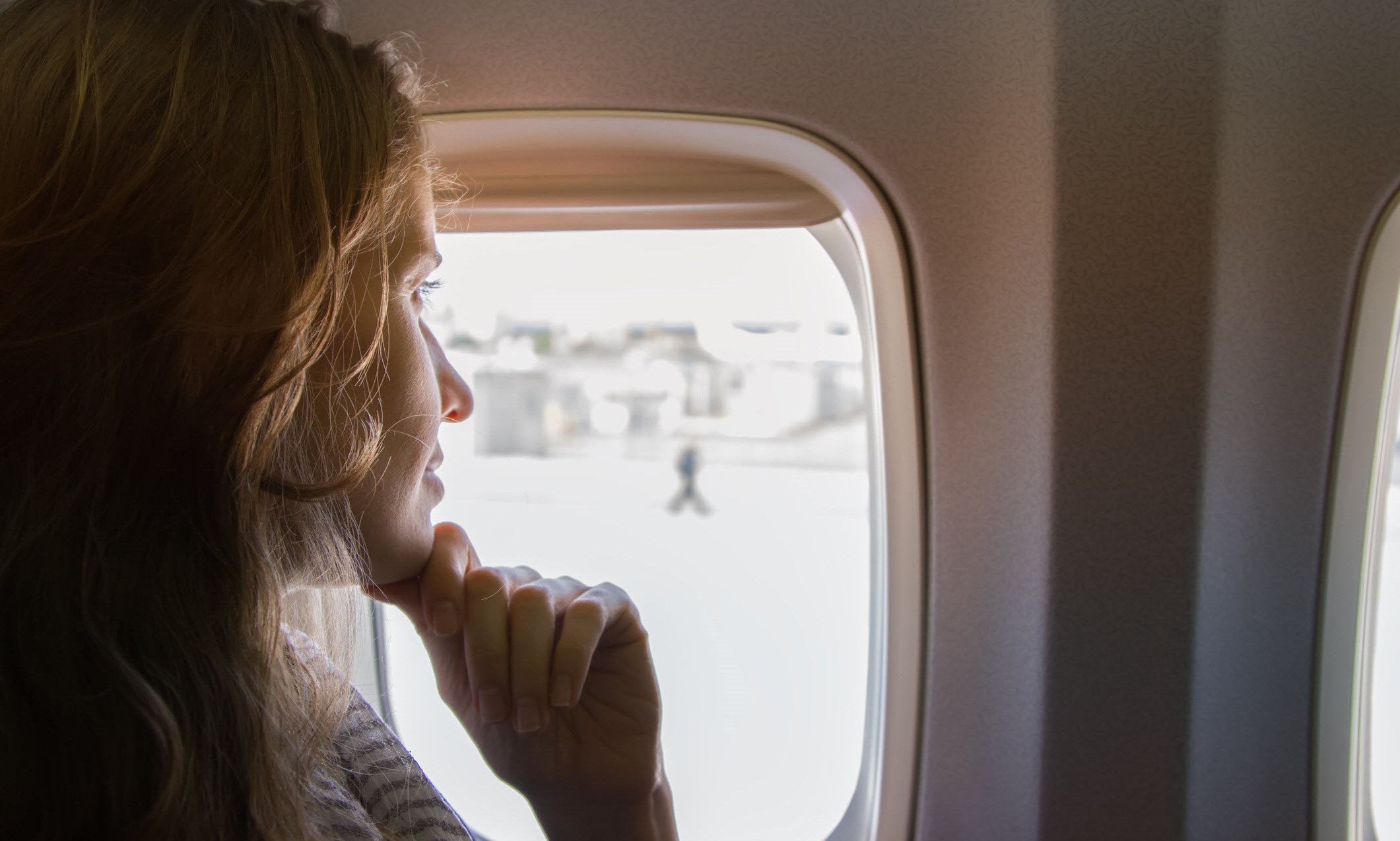 Woman looks out of plane window, confident of her migraine-friendly travelling plans