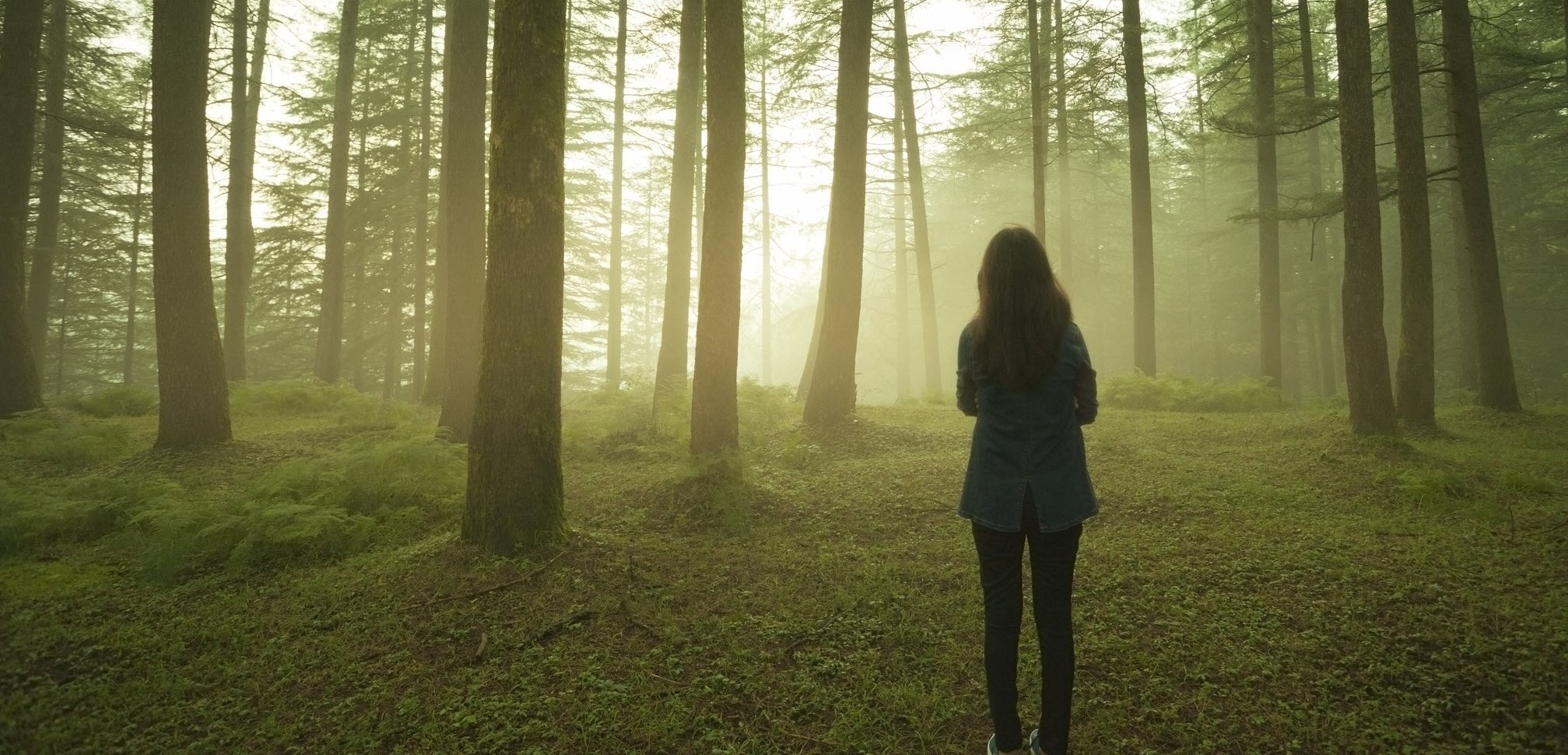 Woman standing alone in the woods, symbolizing the isolation she feels with constant migraine pain