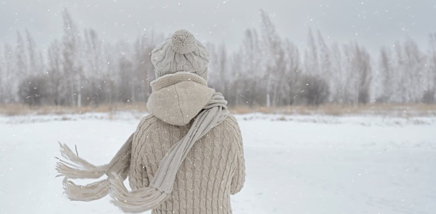 Woman with Christmas depression standing with back to us in the snow