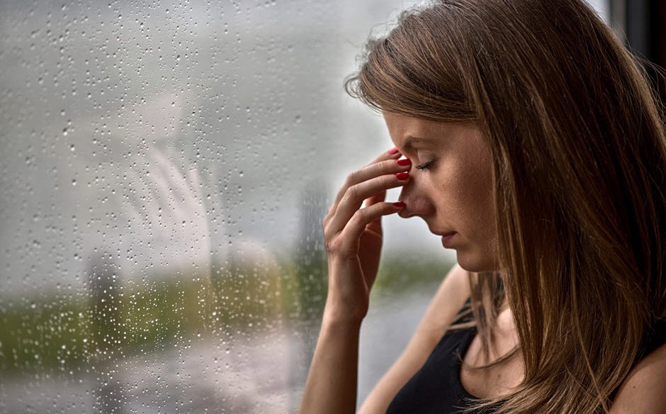 Woman with migraine triggered by barometric pressure shift due to rain